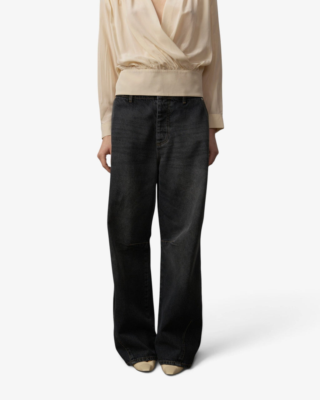 She Stories model wearing Herskind Esme black denim jeans and a long-sleeve cream blouse with a neck tie